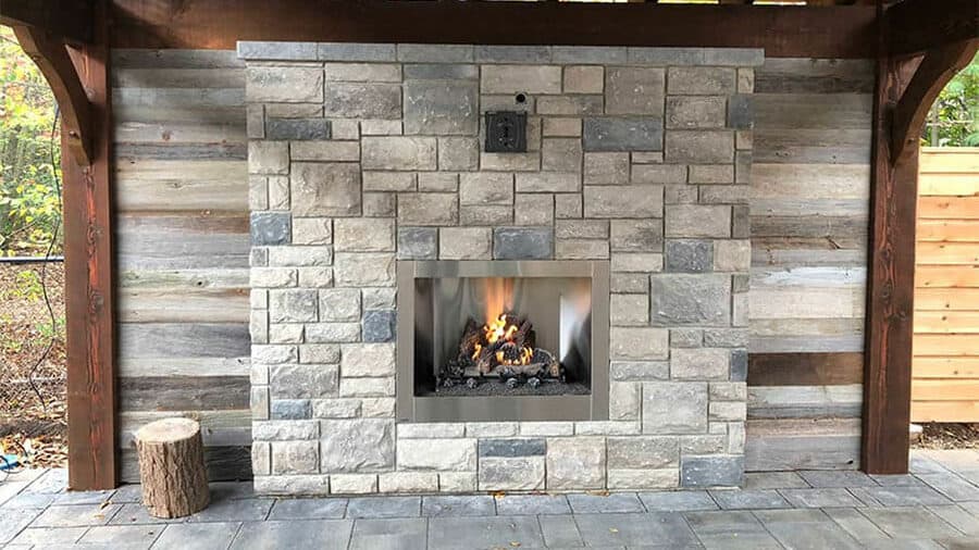 A stone fireplace is built into a wall in an outdoor living space.